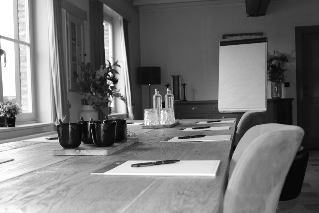 Vergadertafel met schrijfgerief, koffiekopjes en flip-over in een lichte ruimte